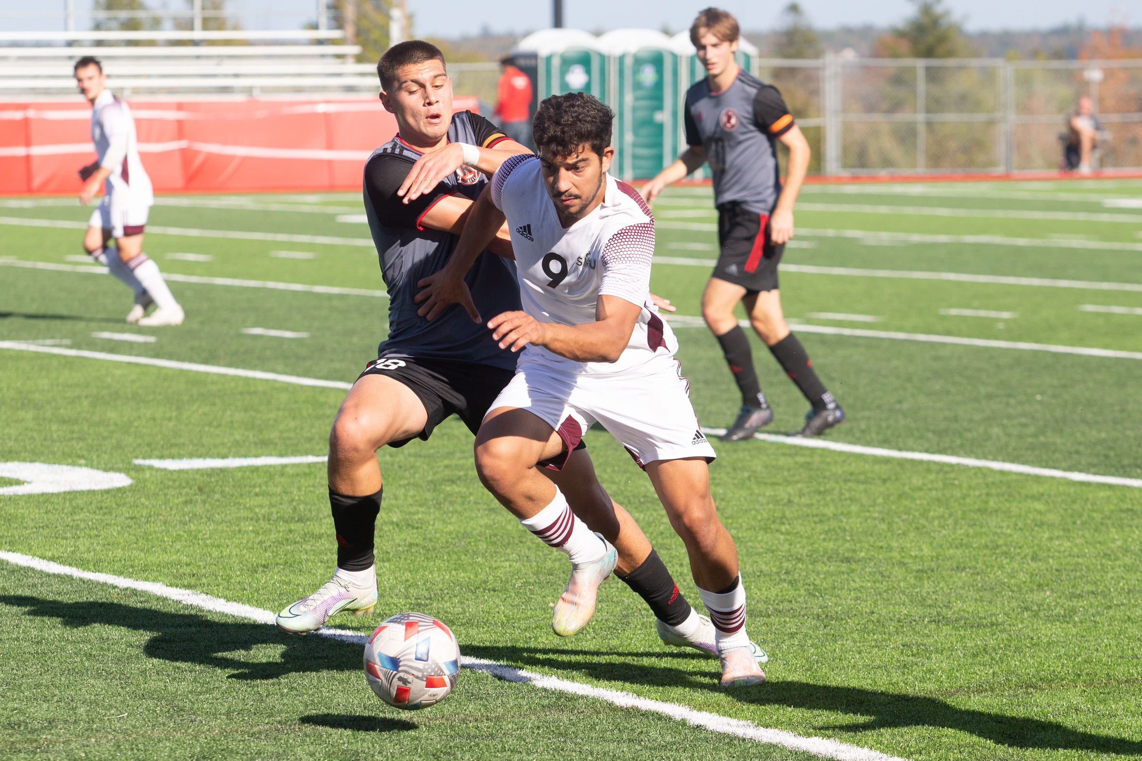 Huskies forward Ahmed Ibrahim (#9) dribbles away from a UNB REDS defender during the Huskies 1-0 win on Oct. 1, 2022 in Fredericton, NB. (Photo courtesy: James West / UNB Athletics)